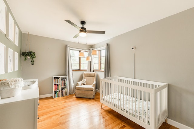 707 Coolidge Pl, Rockford, IL 61107 - bedroom featuring baseboards, light wood-style floors, a crib, and ceiling fan