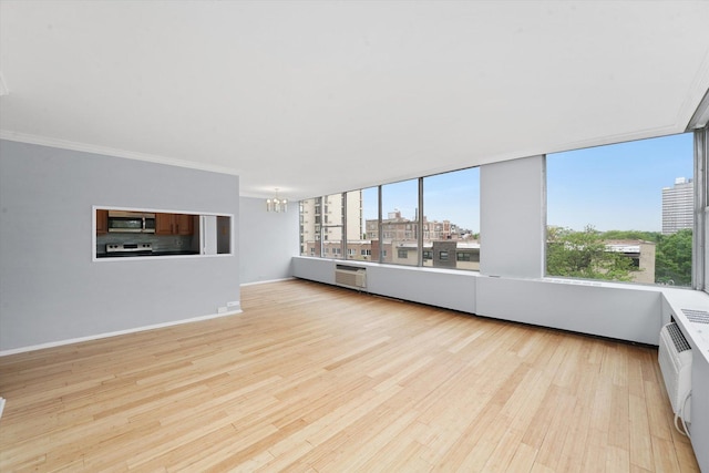 5757 N Sheridan Rd Unit 5J, Chicago, IL 60660 - unfurnished living room featuring a chandelier, light wood-type flooring, an AC wall unit, crown molding, and baseboards