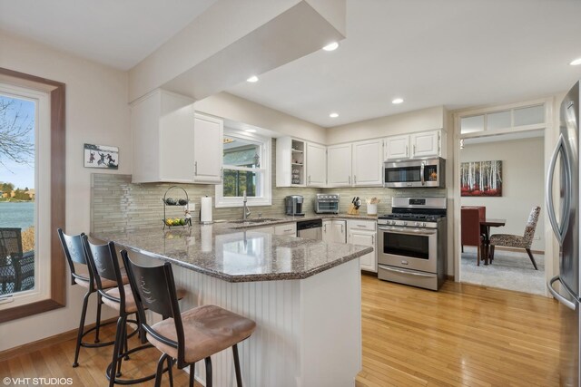 2212 High Point Dr, Lindenhurst, IL 60046 - kitchen with appliances with stainless steel finishes, stone countertops, a sink, a peninsula, and light wood-style flooring