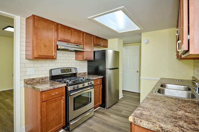 6256 Kit Carson Dr Unit 6256, Hanover Park, IL 60133 - kitchen with appliances with stainless steel finishes, under cabinet range hood, a sink, light wood-style floors, and decorative backsplash