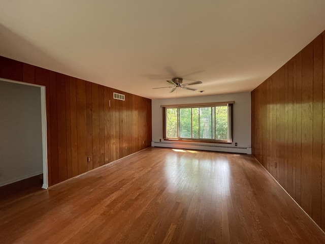 2009 Boehme St, Lockport, IL 60441 - spare room with a baseboard heating unit, wooden walls, ceiling fan, and wood finished floors