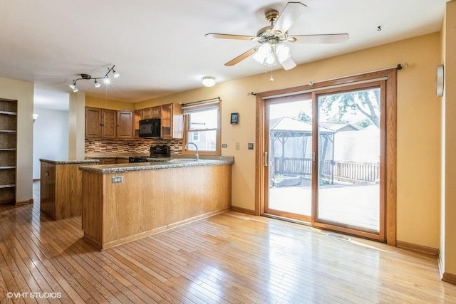 1029 Rain Tree Dr, Bolingbrook, IL 60440 - kitchen with black microwave, range, a peninsula, brown cabinetry, and decorative backsplash