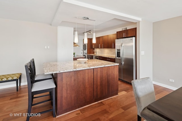 1 E Schiller St Unit 10B, Chicago, IL 60610 - kitchen featuring stainless steel refrigerator with ice dispenser, wood finished floors, baseboards, light stone counters, and a kitchen bar