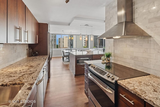 1 E Schiller St Unit 10B, Chicago, IL 60610 - kitchen with wall chimney range hood, stainless steel appliances, dark wood-style flooring, tasteful backsplash, and light stone counters