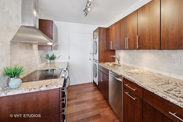 1 E Schiller St Unit 10B, Chicago, IL 60610 - kitchen with wall chimney exhaust hood, stacked washer / drying machine, a sink, stainless steel appliances, and light stone countertops