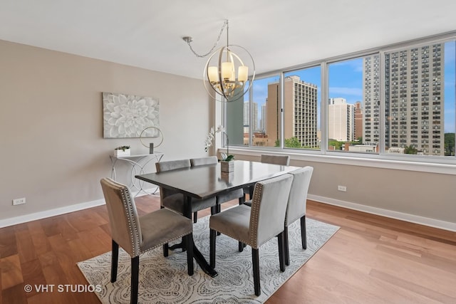 1 E Schiller St Unit 10B, Chicago, IL 60610 - dining room featuring baseboards, a chandelier, a skyline view, and wood finished floors