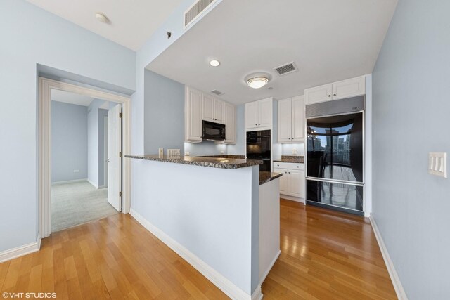 21 E Huron St Unit 1101, Chicago, IL 60611 - kitchen with black appliances, a sink, light wood finished floors, and white cabinetry