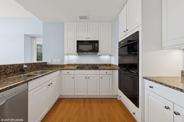 21 E Huron St Unit 1101, Chicago, IL 60611 - kitchen with black appliances, a sink, light wood-type flooring, white cabinetry, and dark stone countertops