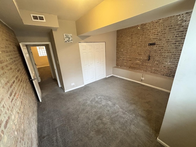 1430 E 69th St Unit 1S, Chicago, IL 60637 - unfurnished bedroom with baseboards, dark colored carpet, a closet, and brick wall