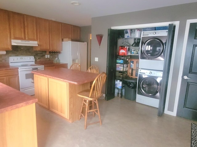 626 Sedgegrass Dr, Champaign, IL 61822 - kitchen with white appliances, stacked washer and clothes dryer, under cabinet range hood, a kitchen bar, and a center island