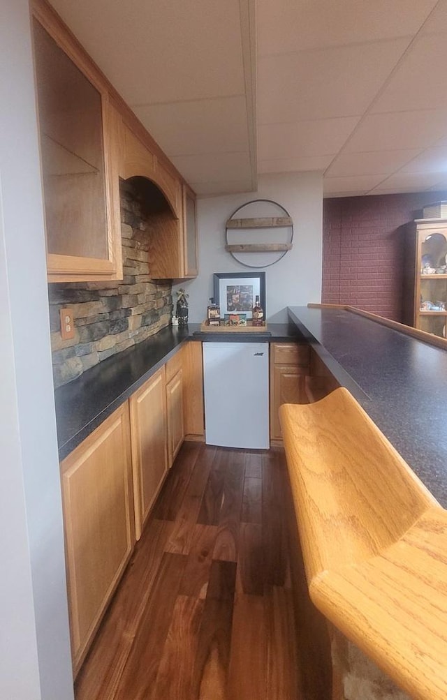 626 Sedgegrass Dr, Champaign, IL 61822 - kitchen featuring a paneled ceiling, dark wood-style flooring, dark countertops, backsplash, and light brown cabinets