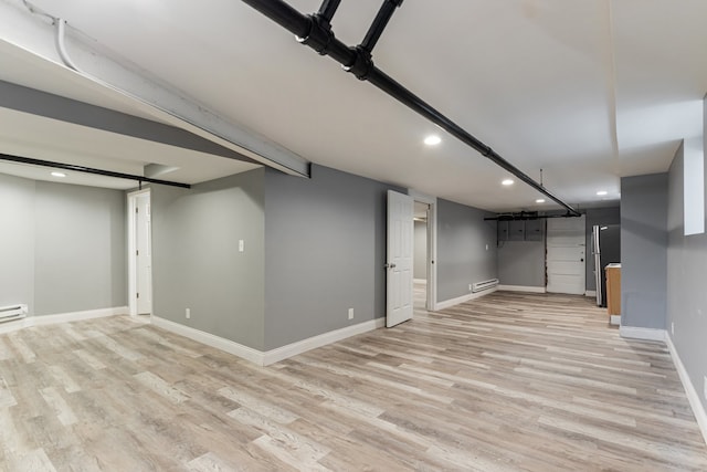 finished basement featuring recessed lighting, light wood-style flooring, baseboards, and a baseboard heating unit