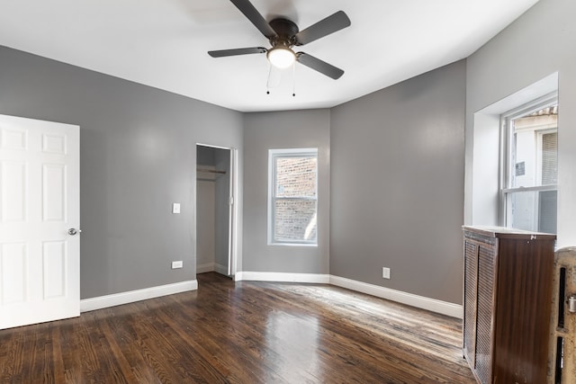 unfurnished bedroom featuring wood finished floors, baseboards, a closet, and a ceiling fan