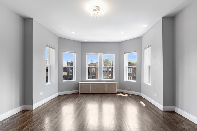 unfurnished room featuring baseboards, dark wood finished floors, and recessed lighting