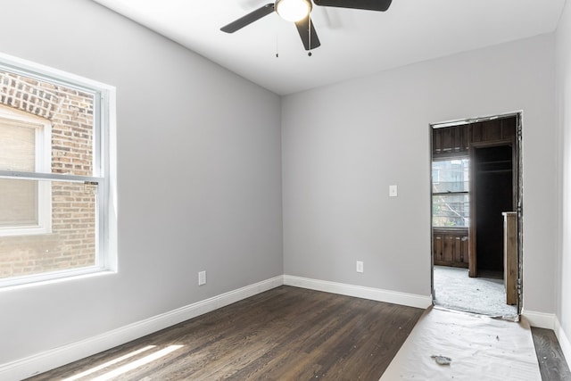 spare room with dark wood-type flooring, ceiling fan, and baseboards