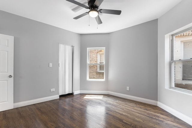 unfurnished room featuring dark wood-style floors, a ceiling fan, and baseboards