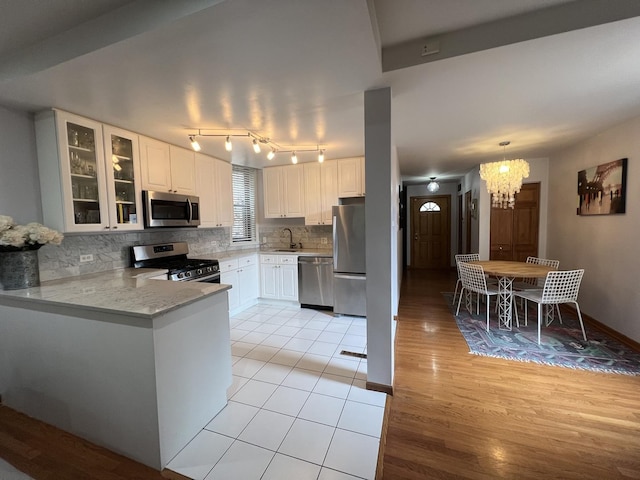 2125 N Clark St Unit 3, Chicago, IL 60614 - kitchen featuring appliances with stainless steel finishes, a chandelier, light wood-style flooring, and glass insert cabinets