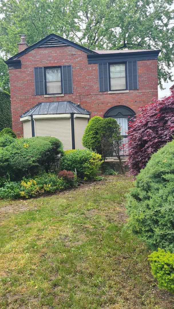 8214 S Yates Blvd, Chicago, IL 60617 - view of front of property featuring a chimney, a front yard, and brick siding