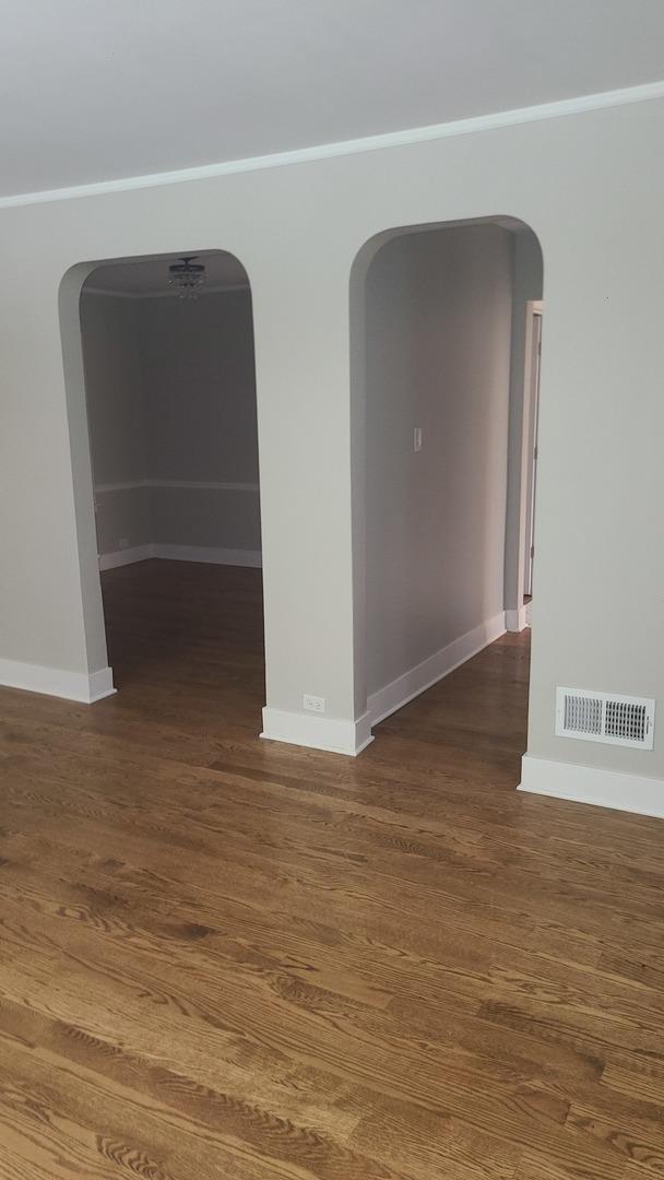 8214 S Yates Blvd, Chicago, IL 60617 - spare room featuring arched walkways, baseboards, wood finished floors, and ornamental molding