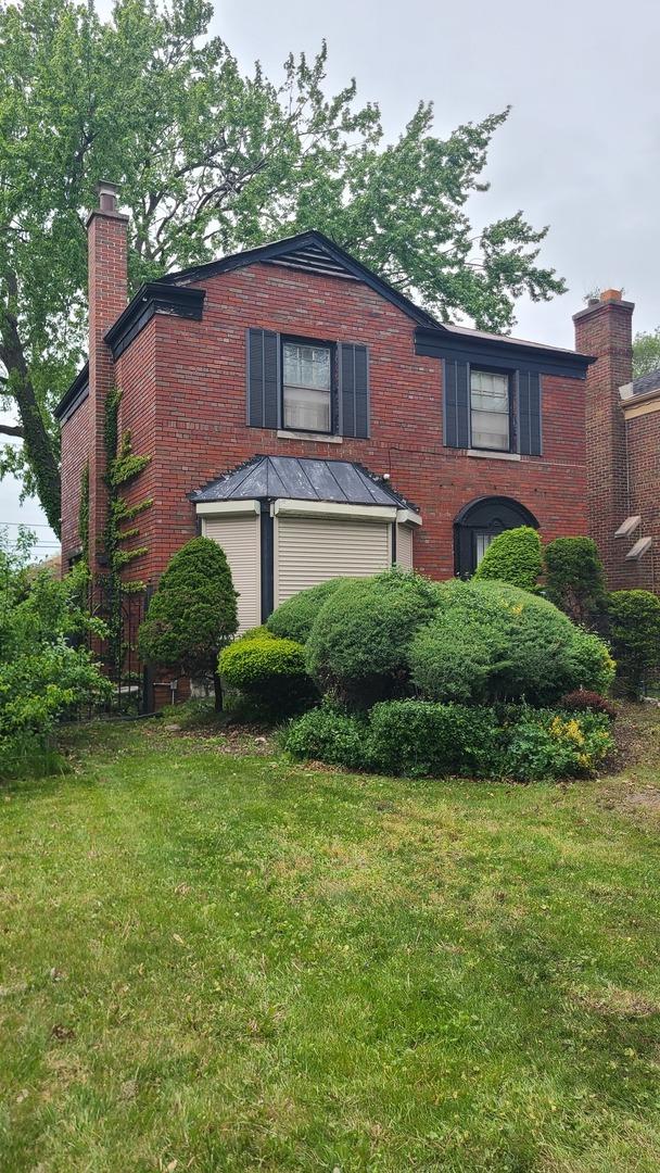 8214 S Yates Blvd, Chicago, IL 60617 - view of front of home with a chimney, a front yard, and brick siding