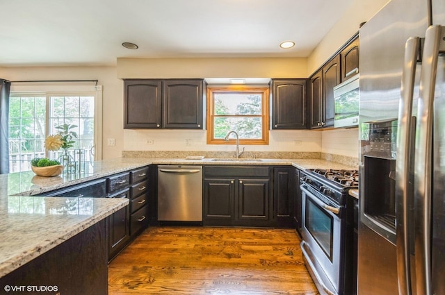 6407 Hillcrest Rd, Cary, IL 60013 - kitchen with appliances with stainless steel finishes, a sink, light stone countertops, dark brown cabinets, and plenty of natural light