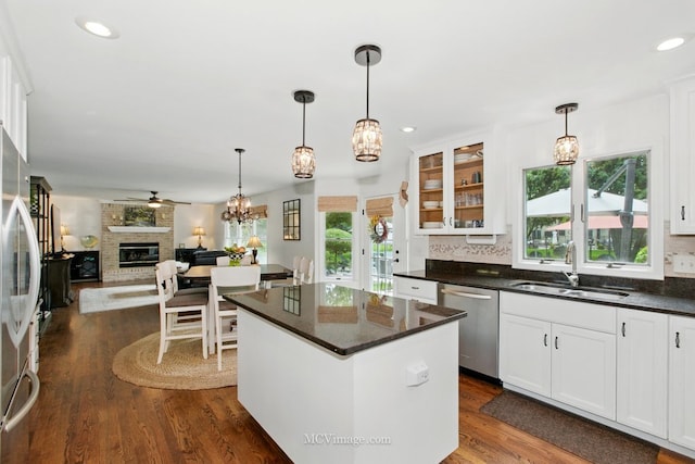 24255 Cropland Dr, Plainfield, IL 60544 - kitchen featuring appliances with stainless steel finishes, a sink, a brick fireplace, glass insert cabinets, and white cabinetry