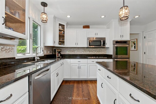 24255 Cropland Dr, Plainfield, IL 60544 - kitchen featuring stainless steel appliances, a sink, dark wood-type flooring, hanging light fixtures, and white cabinetry