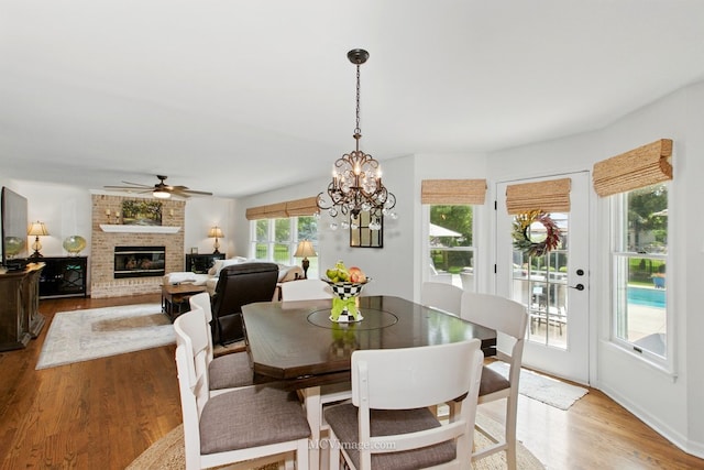 24255 Cropland Dr, Plainfield, IL 60544 - dining area featuring a brick fireplace, light wood finished floors, a ceiling fan, and a chandelier