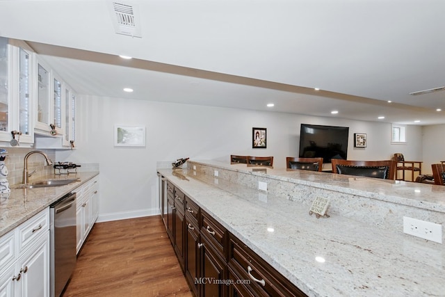 24255 Cropland Dr, Plainfield, IL 60544 - kitchen featuring stainless steel dishwasher, a sink, light wood-style floors, white cabinets, and light stone counters
