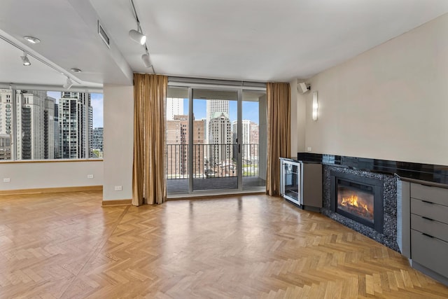 1000 N Lake Shore Plz Unit 17C, Chicago, IL 60611 - unfurnished living room featuring rail lighting, a tiled fireplace, a city view, baseboards, and a wall of windows