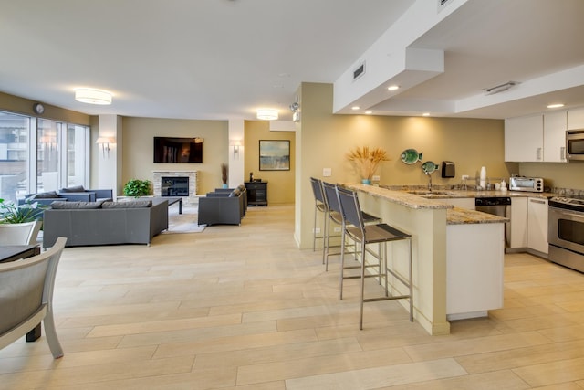 1000 N Lake Shore Plz Unit 17C, Chicago, IL 60611 - kitchen featuring appliances with stainless steel finishes, a peninsula, a breakfast bar area, white cabinetry, and light stone countertops
