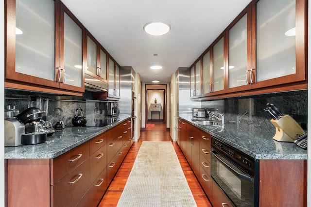 161 E Chicago Ave Unit 33De, Chicago, IL 60611 - kitchen featuring black electric stovetop, wood finished floors, glass insert cabinets, and decorative backsplash