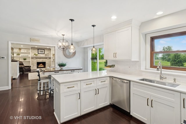 3022 Woods Creek Ln, Algonquin, IL 60102 - kitchen featuring stainless steel dishwasher, a sink, a peninsula, a fireplace, and white cabinets
