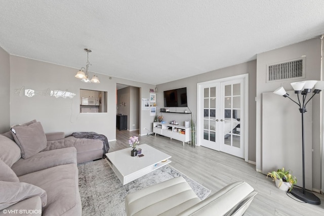 10 E Ontario St Unit 2806, Chicago, IL 60611 - living area with a textured ceiling, wood finished floors, french doors, and a chandelier