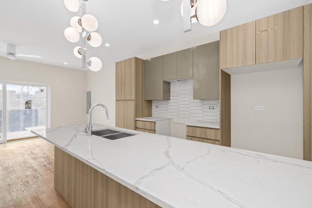 6513 S Langley Ave, Chicago, IL 60637 - kitchen featuring a sink, modern cabinets, light wood-style flooring, light stone countertops, and tasteful backsplash