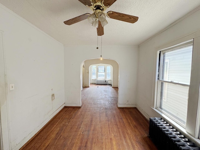 7514 S Rhodes Ave, Chicago, IL 60619 - empty room featuring radiator, arched walkways, a textured ceiling, wood finished floors, and ceiling fan