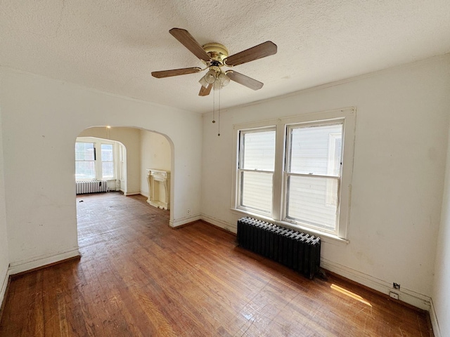 7514 S Rhodes Ave, Chicago, IL 60619 - spare room featuring radiator, arched walkways, a ceiling fan, baseboards, and a textured ceiling