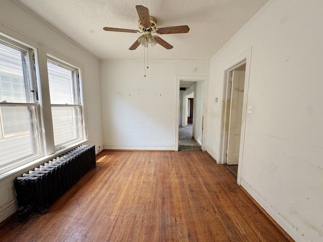 7514 S Rhodes Ave, Chicago, IL 60619 - empty room with radiator heating unit, wood finished floors, a textured ceiling, ceiling fan, and baseboards