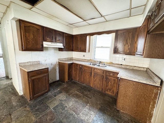 7514 S Rhodes Ave, Chicago, IL 60619 - kitchen with a sink, under cabinet range hood, stone tile floors, and decorative backsplash