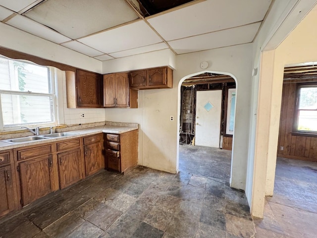 7514 S Rhodes Ave, Chicago, IL 60619 - kitchen featuring a sink, arched walkways, dark stone finish flooring, light countertops, and brown cabinets