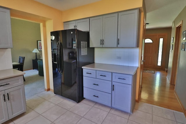 523 Jaquays St, Lockport, IL 60441 - kitchen with black refrigerator with ice dispenser, backsplash, light countertops, and light tile patterned floors