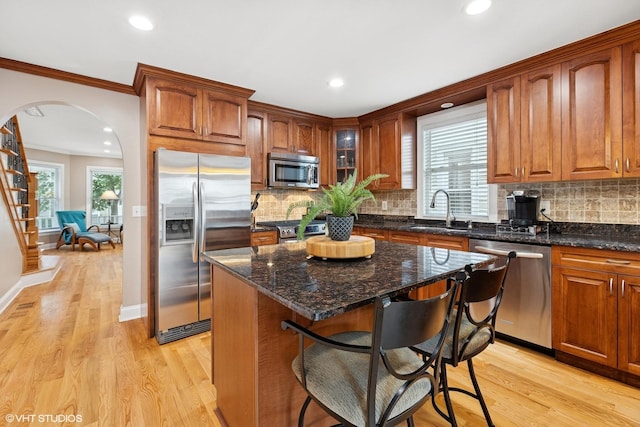 1513 W Highland Ave, Chicago, IL 60660 - kitchen with stainless steel appliances, arched walkways, light wood-type flooring, crown molding, and a kitchen breakfast bar
