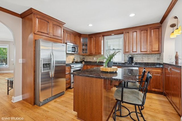 1513 W Highland Ave, Chicago, IL 60660 - kitchen with stainless steel appliances, light wood finished floors, arched walkways, ornamental molding, and decorative backsplash