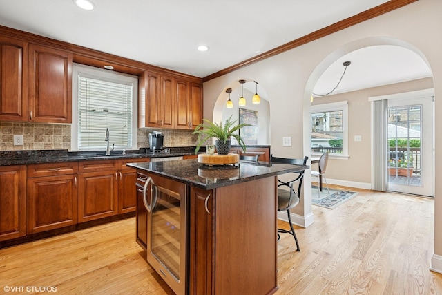 1513 W Highland Ave, Chicago, IL 60660 - kitchen featuring beverage cooler, arched walkways, a kitchen bar, tasteful backsplash, and light wood-style flooring
