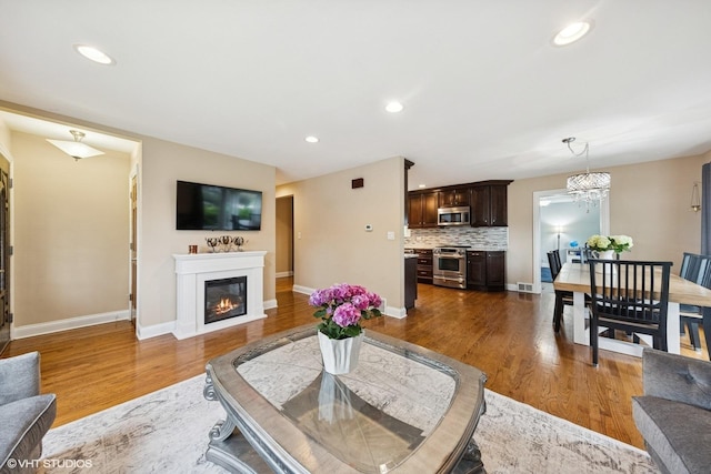 5112 N Canfield Ave, Norridge, IL 60706 - living room with dark wood-style floors, baseboards, a glass covered fireplace, recessed lighting, and a chandelier