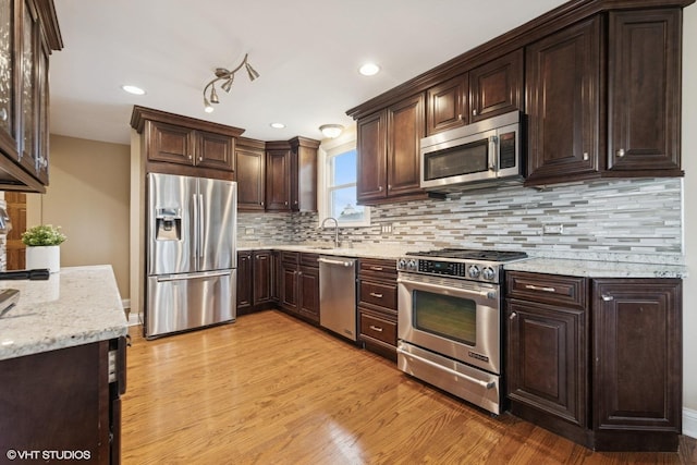 5112 N Canfield Ave, Norridge, IL 60706 - kitchen with appliances with stainless steel finishes, light wood finished floors, dark brown cabinetry, light stone countertops, and tasteful backsplash