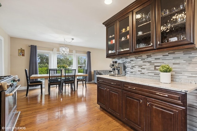 5112 N Canfield Ave, Norridge, IL 60706 - bar area featuring stainless steel stove, tasteful backsplash, light wood-style floors, a chandelier, and baseboards