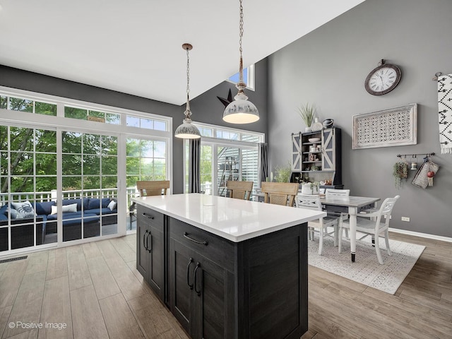 1016 Hummingbird Way, Bartlett, IL 60103 - kitchen with dark cabinetry, high vaulted ceiling, light wood-style floors, light countertops, and pendant lighting