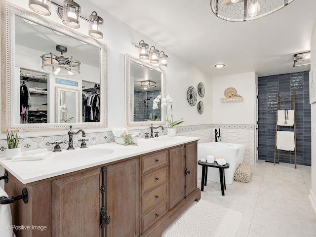 1016 Hummingbird Way, Bartlett, IL 60103 - bathroom featuring tile walls, double vanity, a freestanding bath, a spacious closet, and tile patterned floors