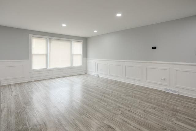 615 E 101st Pl, Chicago, IL 60628 - unfurnished room with wainscoting, a decorative wall, wood finished floors, and recessed lighting